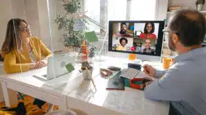 two employees in an office on a call with remote employees representing new reality of hybrid teams in the workplace