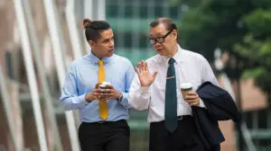 senior business man walking with junior business man implementing mentoring at work